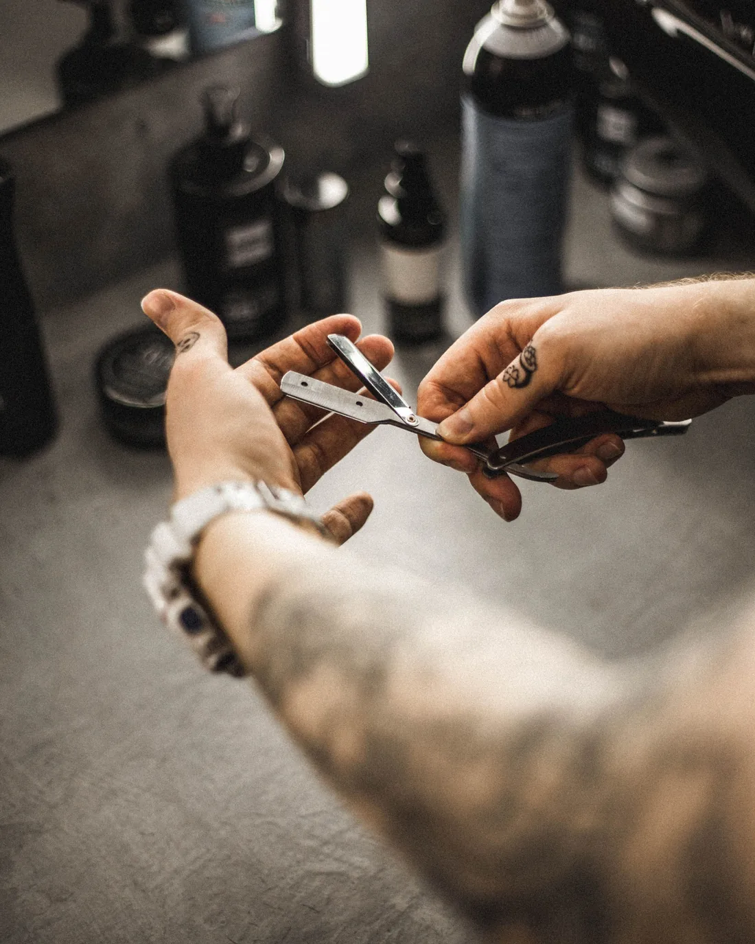Main tatouée du barbier tenant une paire de ciseaux