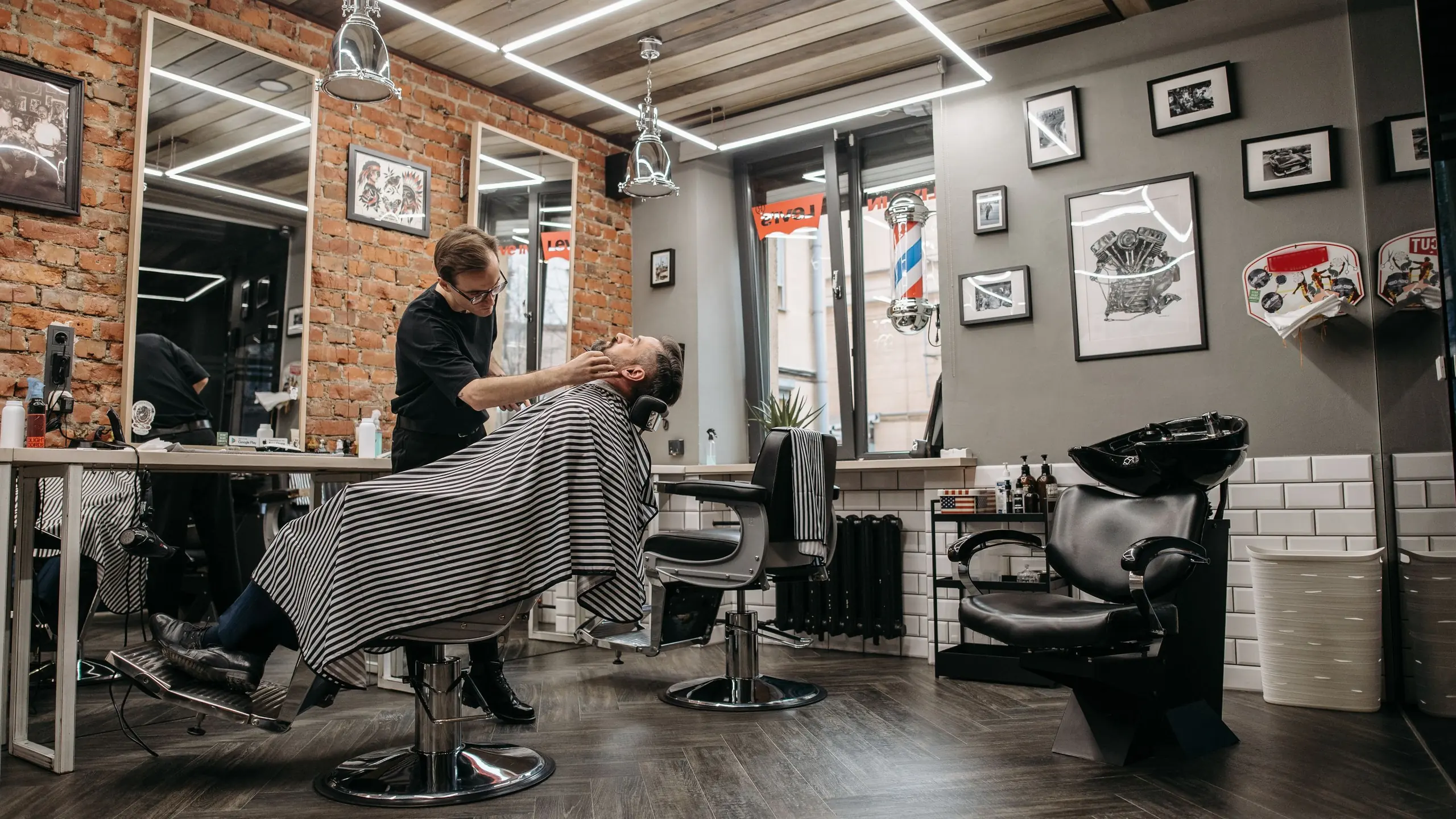 Un barbier au travail sur un client, au fond de la salle